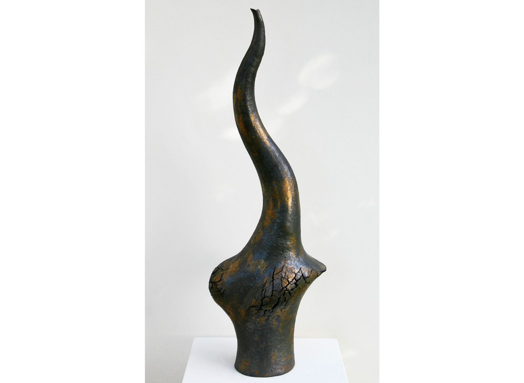 Tall curvacious black sculpture with gold flecks and cracks, called The Coming of Age
